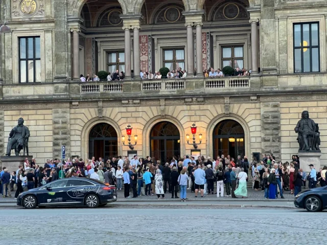 Publikum foran Det Kongelige Teater. Et glimt af bylivet omkring udstillingen. Publikum foran Det Kongelige Teater. Et glimt af bylivet omkring udstillingen.
